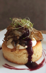 Delicate dish with a pastry base, cream, and garnishes on a white plate.